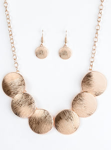 Embossed in shimmery linear patterns, round rose gold frames link below the collar for a bold industrial look. Features an adjustable clasp closure.  Sold as one individual necklace. Includes one pair of matching earrings.