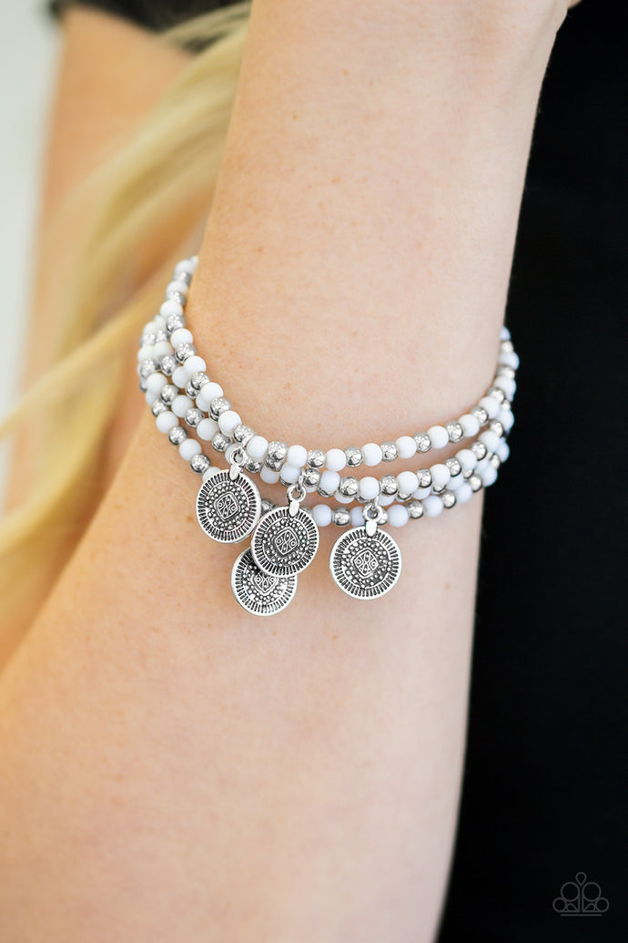 Dainty white and beads are threaded along stretchy elastic bands, creating colorful layers across the wrist. Brushed in an antiqued shimmer, ornate silver charms swing from the wrist for a wanderlust finish.  Sold as one set of four bracelets.  Always nickel and lead free.