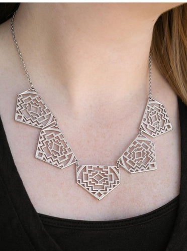Shimmery metallic plates swing from a classic silver chain, creating a geometric fringe. Decorated in a Southwestern textile pattern, the stenciled plates fall just below the collar in an airy fashion. Features an adjustable clasp closure.  Sold as one individual necklace. Includes one pair of matching earrings.