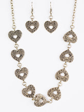 Load image into Gallery viewer, Vintage inspired heart frames link below the collar, creating a whimsical chain. Brushed in an antiqued finish, filigree delicately climbs the brass hearts for an ornate finish. Features an adjustable clasp closure.  Sold as one individual necklace. Includes one pair of matching earrings.