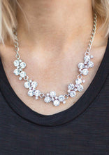 Load image into Gallery viewer, A row of dazzling white rhinestones drapes along the neckline, creating a sparkling display. Daintier white rhinestones are sprinkled along the clusters, adding luminous detail to the timeless design. Features an adjustable clasp closure.  Sold as one individual necklace. Includes one pair of matching earrings.