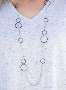 Tinted in a bold finish, shiny black hoops trickle along dainty silver chain, creating a colorful asymmetrical palette. Features an adjustable clasp closure.  Sold as one individual necklace. Includes one pair of matching earrings.  