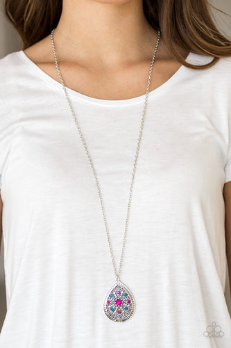 A dramatic teardrop pendant swings from the bottom of an elongated silver chain, elegantly slimming the torso. Glittery blue and pink rhinestones are sprinkled along the pendant as silver filigree dances across the center, creating a regal floral pattern. Features an adjustable clasp closure.  Sold as one individual necklace. Includes one pair of matching earrings. 