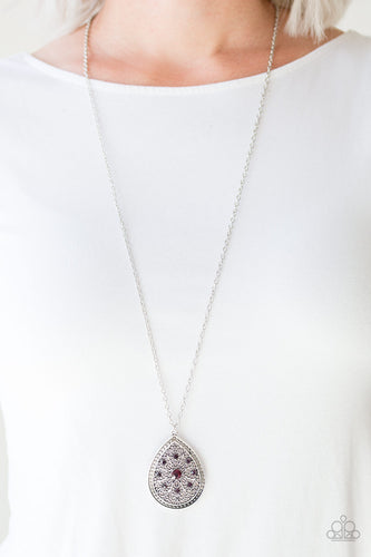 A dramatic teardrop pendant swings from the bottom of an elongated silver chain, elegantly slimming the torso. Glittery purple rhinestones are sprinkled along the pendant as silver filigree dances across the center, creating a regal floral pattern. Features an adjustable clasp closure.  Sold as one individual necklace. Includes one pair of matching earrings. 