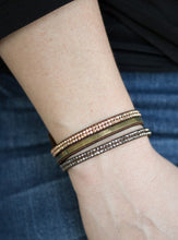Load image into Gallery viewer, A brown suede band is spliced into three strands featuring rows of glittery hematite rhinestones, flat brass chain, and faceted metallic rhinestones for a glamorous look. Features an adjustable snap closure. Sold as one individual bracelet. 