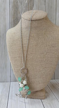 Load image into Gallery viewer, A silver bird charm, silver heart charms, and collection of white pearls and opaque green  crystal-like beads swing from the bottom of a lengthened silver chain for a whimsically clustered look. Features an adjustable clasp closure.  Sold as one individual necklace. Includes one pair of matching earrings.  Exclusive!