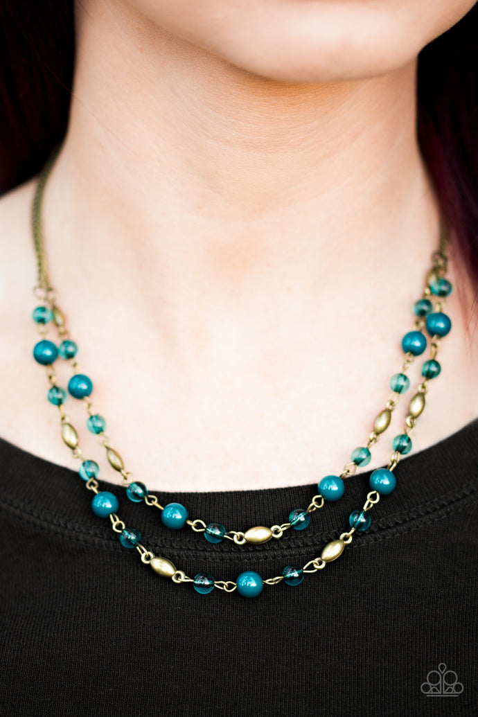 Rustic blue beads trickle along two strands of shimmery brass chain. Infused with shiny brass beading, blue crystal like beads trickle between the colorful accents, creating whimsical layers below the collar. Features an adjustable clasp closure.   Sold as one individual necklace. Includes one pair of matching earrings.   Always nickel and lead free.