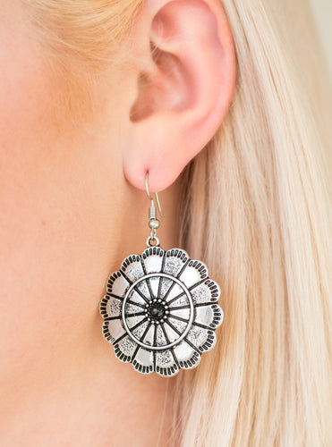 Shimmery silver petals bloom from a black center for a seasonal look. Etched in serrated edges, alternating petals have been delicately hammered in texture, adding depth and shimmer to the whimsical frame. Earring attaches to a standard fishhook fitting.  Sold as one pair of earrings.