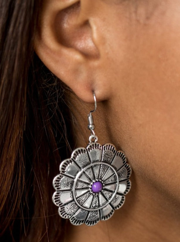 Shimmery silver petals bloom from a vivacious purple center for a seasonal look. Etched in serrated edges, alternating petals have been delicately hammered in texture, adding depth and shimmer to the whimsical frame. Earring attaches to a standard fishhook fitting.  Sold as one pair of earrings.