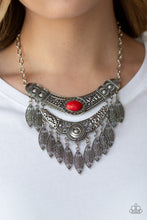 Load image into Gallery viewer, Featuring a collision of hammered, studded, and embossed patterns, two silver half-moon plates dramatically stack below the collar. Swirling with studded filigree detail, ornate silver frames swing from the bottoms of the stacked pendants, creating a fierce tribal inspired fringe. A fiery red stone is pressed into the center of the uppermost frame for a seasonal finish. Features an adjustable clasp closure.  Sold as one individual necklace. Includes one pair of matching earrings.