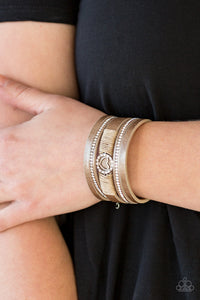 Brushed in a metallic shimmer, strips of brown leather are encrusted in alternating rows of glittery white rhinestones. Brown cording knots around the centermost strand, securing a sparkling heart frame in place for a whimsical finish. Features an adjustable clasp closure.  Sold as one individual bracelet. Always nickel and lead free.