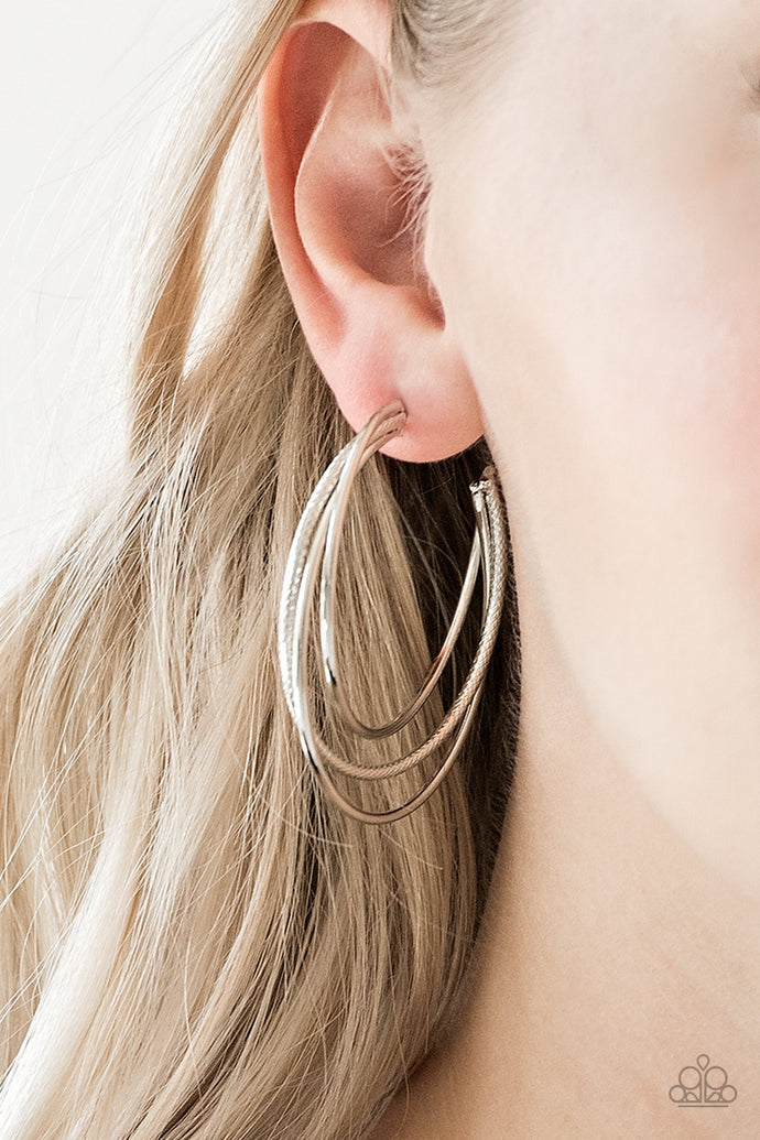 Featuring smooth and serrated finishes, shiny silver frames layer into a bold hoop for a spunky industrial flair. Earring attaches to a standard post fitting. Hoop measures 1 3/4
