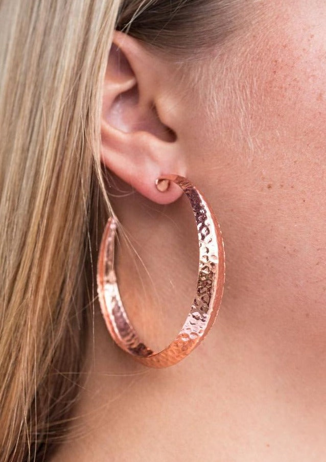 A thick copper hoop creases at the center, creating a chic 3-dimensional display. Finished in a hammered surface, the antiqued design evokes an indigenous inspired style. Earring attaches to standard post fitting. Hoop measures 2 1/4