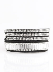 Encrusted in mismatched sparkle, half of a black suede band is encrusted in white emerald style cut rhinestones, while the other half splits into three separate bands encrusted in white rhinestones for a sassy look. The elongated band allows for a trendy double wrap design. Features an adjustable snap closure.  Sold as one individual bracelet.