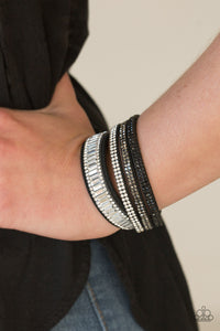 Encrusted in mismatched sparkle, half of a black suede band is encrusted in white emerald style cut rhinestones, while the other half splits into three separate bands encrusted in white, hematite, and black rhinestones for a sassy look. The elongated band allows for a trendy double wrap design. Features an adjustable snap closure.  Sold as one individual bracelet.  Always nickel and lead free.