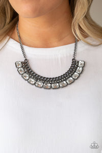 Stationary rows of shimmery gunmetal chain, glittery hematite rhinestones, and glassy white emerald-cut gems coalesce into a bold pendant below the collar. Features an adjustable clasp closure.  Sold as one individual necklace. Includes one pair of matching earrings. Always nickel and lead free.
