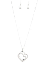 Load image into Gallery viewer, Encrusted in sections of glittery white rhinestones, two glistening silver hearts delicately join at the bottom of a lengthened silver chain for a charming look. Features an adjustable clasp closure.  Sold as one individual necklace. Includes one pair of matching earrings. 