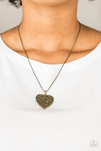 Filled with vine-like filigree detail, a brass heart pendant swings below the collar for a vintage inspired look. Features an adjustable clasp closure.  Sold as one individual necklace. Includes one pair of matching earrings.  Always nickel and lead free.