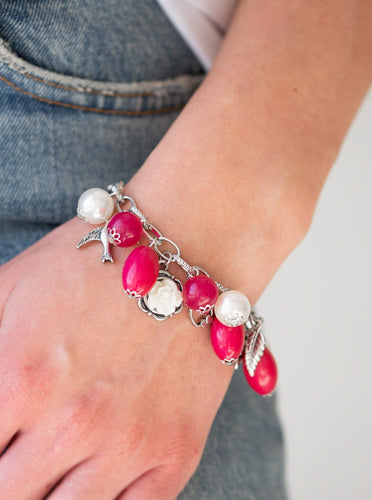 Gorgeous pearls, shiny pink beading, and a collection of shiny silver charms, including a bird and a feather, dance around the wrist in a whimsical fashion. Features an adjustable clasp closure.  Sold as one individual bracelet.