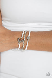 Featuring a gray resin rose and a shimmery silver heart charm, dainty white beads and faceted silver beads are threaded along stretchy bands for a vintage inspired look.  Sold as one set of three bracelets.  Always nickel and lead free.