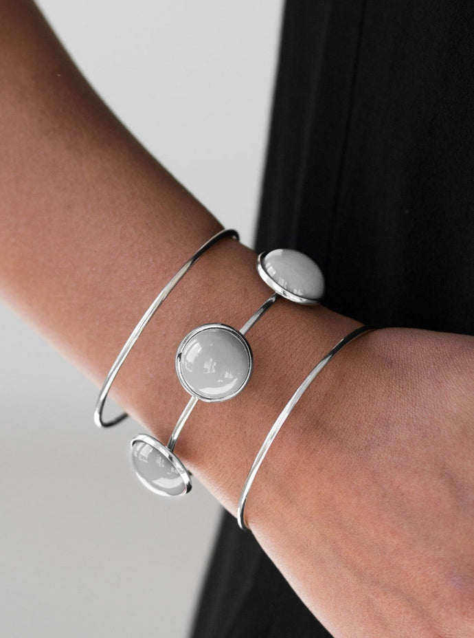Three shimmery silver bars arc across the wrist, coalescing into an airy cuff. Three neutral gray beads are pressed into the center most bar for a bubbly finish.  Sold as one individual bracelet.