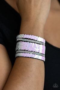 Infused with strands of blinding white rhinestones, row after row of shimmery sequins are stitched across the front of a spliced black suede band. Bracelet features reversible sequins that change from white to multicolored. Features an adjustable snap closure.  Sold as one individual bracelet.  Always nickel and lead free.