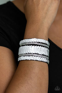 Infused with strands of blinding white rhinestones, row after row of shimmery sequins are stitched across the front of a spliced black suede band. Bracelet features reversible sequins that change from white to multicolored. Features an adjustable snap closure.  Sold as one individual bracelet.  Always nickel and lead free.