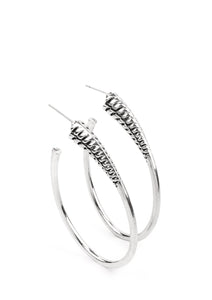 A spiral of texture resembling a coil anchors an exaggerated oblong silver hoop that wraps around the ear. The high-sheen finish on the curved bar adds a hint of drama, as it refracts the light in a knockout finish. Earring attaches to a standard post fitting. Hoop measures approximately 1 1/2" in diameter.