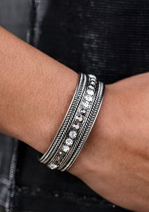 A row of glittery white and hematite rhinestones line the center of a studded silver cuff for an edgy look.