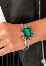 Load image into Gallery viewer, A dramatic emerald green gem is pressed into the center of textured silver frame, e.creating a glamorous centerpiece atop an airy silver cuff. Features a hinged closure.