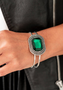 A dramatic emerald green gem is pressed into the center of textured silver frame, e.creating a glamorous centerpiece atop an airy silver cuff. Features a hinged closure.