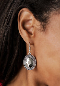 An over sized hematite gem is pressed into a round silver frame encrusted in stacked rings of smoky rhinestones for a blinding finish. Earring attaches to a standard fishhook fitting.