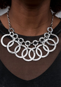 A collection of large and small silver hoops hammered in blinding texture swing from the bottom of interconnected hammered links, creating an edgy industrial fringe below the collar. Features an adjustable clasp closure.