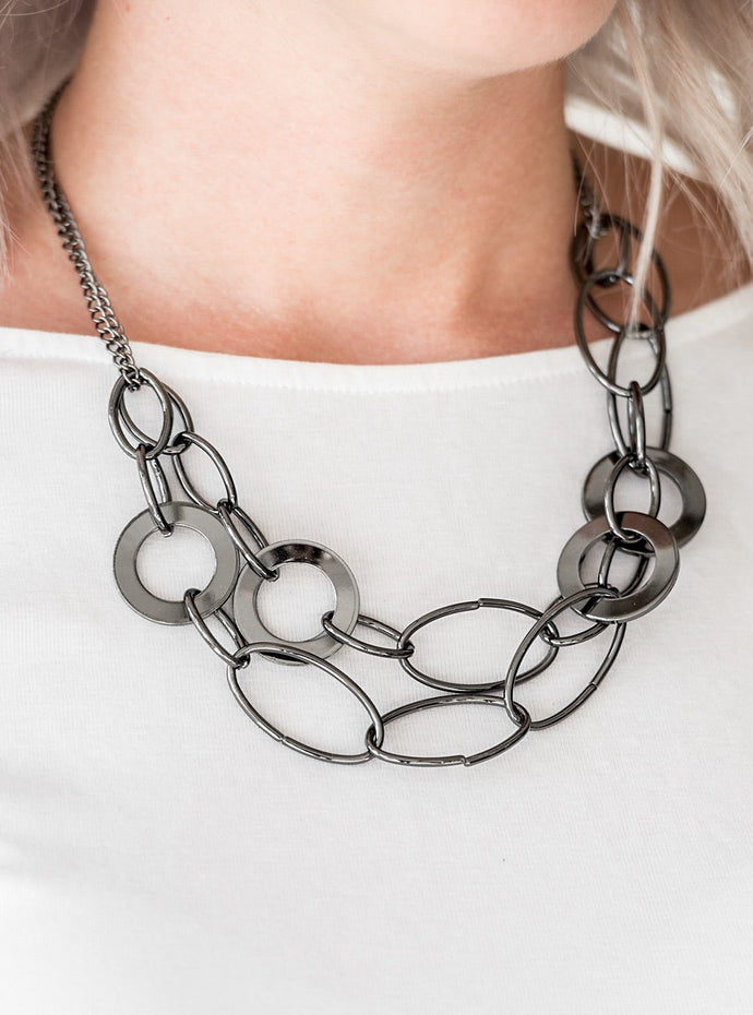 Mismatched gunmetal rings and hoops link below the collar in bold layers for a spunky industrial look. Features an adjustable clasp closure.  Sold as one individual necklace. Includes one pair of matching earrings. 