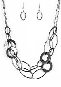 Mismatched gunmetal rings and hoops link below the collar in bold layers for a spunky industrial look. Features an adjustable clasp closure.  Sold as one individual necklace. Includes one pair of matching earrings.