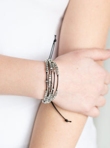A collection of dainty silver beads and glistening silver cubes are threaded along strands of shiny black cording around the wrist for a minimalist inspired look. Features an adjustable sliding knot closure.  Sold as one individual bracelet.