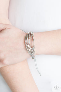 A collection of dainty silver beads and glistening silver cubes are threaded along strands of shiny gray cording around the wrist for a minimalist inspired look. Features an adjustable sliding knot closure.  Sold as one individual bracelet.  Always nickel and lead free.