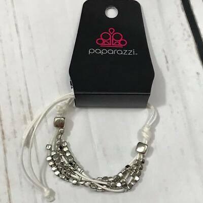 A collection of dainty silver beads and glistening silver cubes are threaded along strands of white gray cording around the wrist for a minimalist inspired look. Features an adjustable sliding knot closure.  Sold as one individual bracelet.  Always nickel and lead free.  Fashion Fix Exclusive