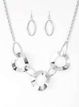 Load image into Gallery viewer, Featuring slightly warped surfaces, asymmetrical silver hoops link with reflective silver rings below the collar for a modern look. Features an adjustable clasp closure.  Sold as one individual necklace. Includes one pair of matching earrings.