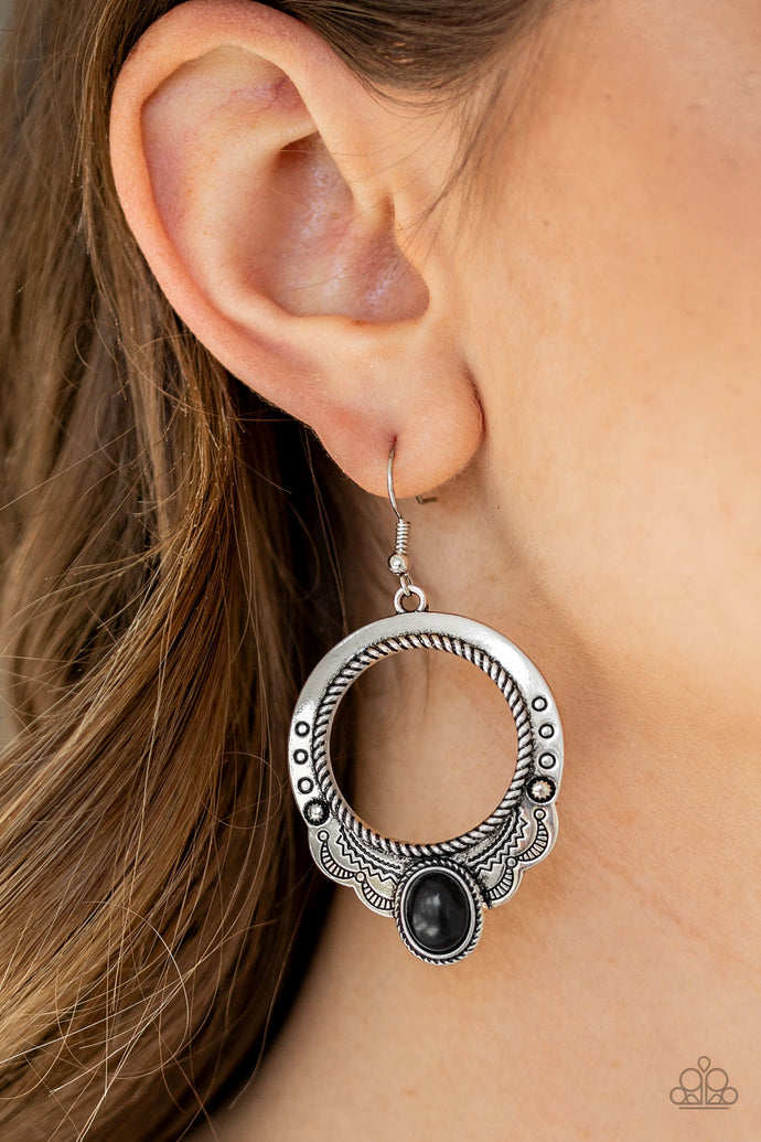 An oval black stone is pressed into the bottom of a scalloped silver hoop stamped and studded in trendy patterns for a southwestern inspired look. Earring attaches to a standard fishhook fitting.  Sold as one pair of earrings.  Always nickel and lead free.