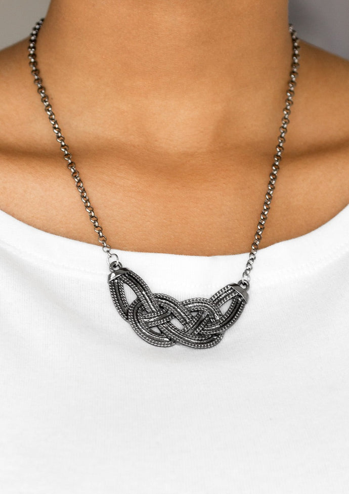 Featuring chain-like patterns, antiqued gunmetal bars knot below the collar for a bold industrial look. Features an adjustable clasp closure.  Sold as one individual necklace. Includes one pair of matching earrings. 