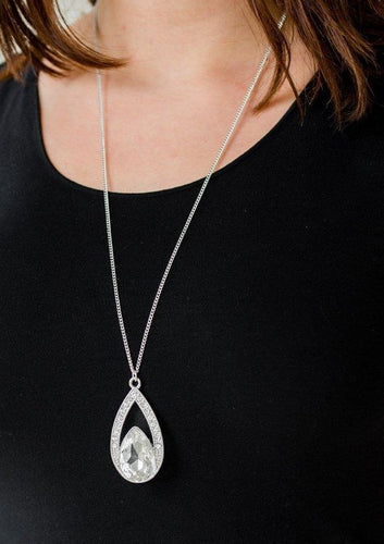 A glittery white teardrop gem is pressed into a silver frame radiating with glassy white rhinestones. The glamorous pendant swings from the bottom of a shimmery silver chain for a refined look. Features an adjustable clasp closure.  Sold as one individual necklace. Includes one pair of matching earrings.  Always nickel and lead free.