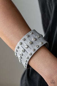 Pressed into sleek silver frames, glittery white rhinestones are studded across a thick gray leather band featuring a center lined with slits for a sassy finish. Features an adjustable snap closure.  Sold as one individual bracelet.  Always nickel and lead free.