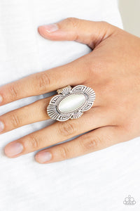 A white oval cat's eye stone is pressed into the center of a scalloped silver frame radiating with linear detail for a whimsical flair. Features a stretchy band for a flexible fit.  Sold as one individual ring.  Always nickel and lead free.