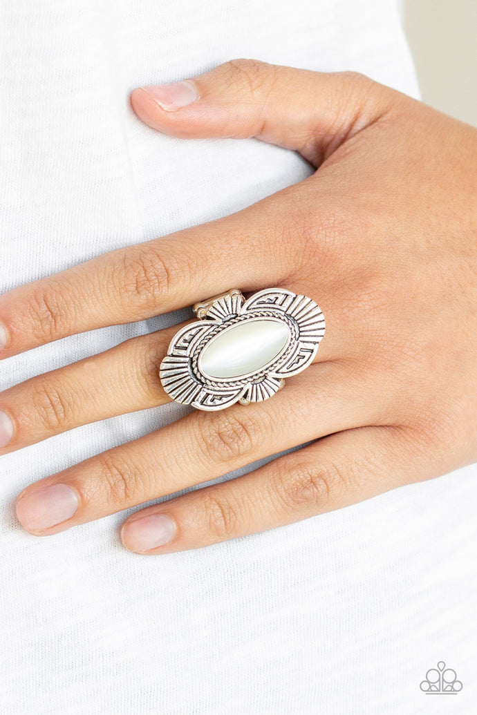 A white oval cat's eye stone is pressed into the center of a scalloped silver frame radiating with linear detail for a whimsical flair. Features a stretchy band for a flexible fit.  Sold as one individual ring.  Always nickel and lead free.