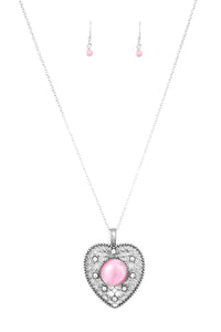 Featuring a glowing pink moonstone center, an over-sized heart frame radiating with silver filigree and glittery white rhinestones swings from the bottom of a lengthened silver chain for a whimsical look. Features an adjustable clasp closure.  Sold as one individual necklace. Includes one pair of matching earrings.