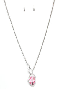 A faceted pink gem is nestled inside of a shimmery silver frame encrusted in dainty white rhinestones. The glittery pendant asymmetrically links with abstract silver frames at the bottom of a lengthened silver rounded snake chain for a modern look. Features an adjustable clasp closure.  Sold as one individual necklace. Includes one pair of matching earrings.