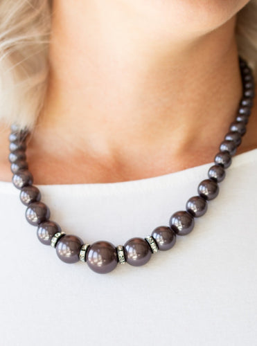 Gradually increasing in size, pearly gunmetal beads trickle below the collar for a classic look. Encrusted in dazzling white rhinestones, glittery rings are sprinkled between the pearls for a timeless finish. Features an adjustable clasp closure.  Sold as one individual necklace. Includes one pair of matching earrings. 