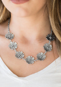 Featuring lifelike detail, a row of shimmery silver flowers links below the collar for a seasonal look. Features an adjustable clasp closure.  Sold as one individual necklace. Includes one pair of matching earrings.