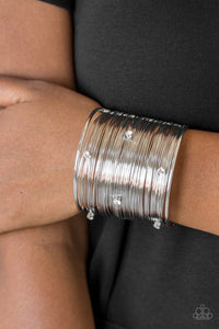 Shimmery silver wires wrap back and forth along a silver frame, creating a bold cuff. Glassy white rhinestones are sprinkled across the dramatic cuff for a glamorous finish.  Sold as one individual bracelet.  Always nickel and lead free.